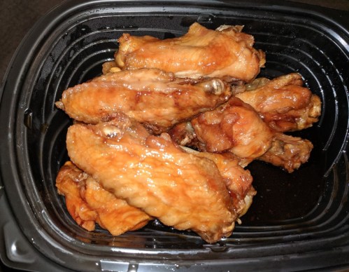 A container filled with glazed chicken wings, showcasing their shiny, caramelized surface.