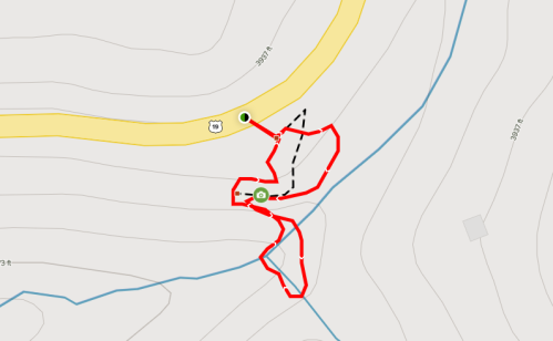 Map showing a trail with red and black paths, indicating routes near a yellow road and elevation lines.