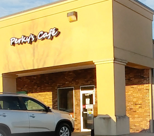 Exterior of Perky's Cafe with a car parked in front, featuring a warm, inviting facade and clear signage.