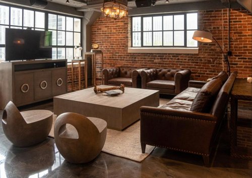 Stylish industrial living room with brick walls, leather sofas, a concrete coffee table, and modern decor.