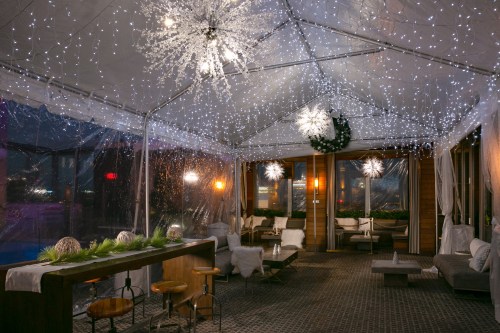 A cozy, decorated tent with fairy lights, snowflake ornaments, and comfortable seating for a festive atmosphere.