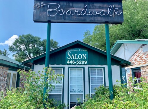 A small salon building with a sign reading "The Boardwalk" and "Arkansas House Salon" in a green and white color scheme.
