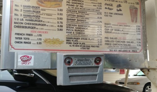 Menu board featuring various food items and prices, including burgers, sandwiches, and sides, at a drive-in restaurant.