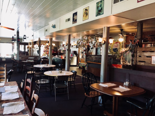 Cozy restaurant interior with wooden tables, chairs, and decorative plants, featuring a warm, inviting atmosphere.