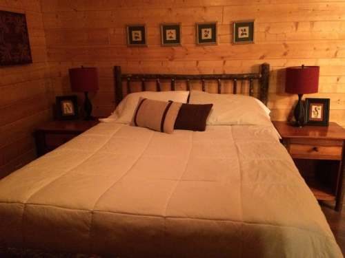 Cozy bedroom with a wooden bed, white bedding, and bedside tables with lamps and framed pictures on the walls.