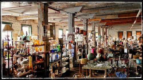 A spacious antique shop filled with various vintage items, furniture, and decor under natural light.