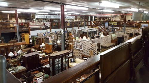 A spacious antique store filled with various furniture, lamps, and decor items arranged throughout the large area.