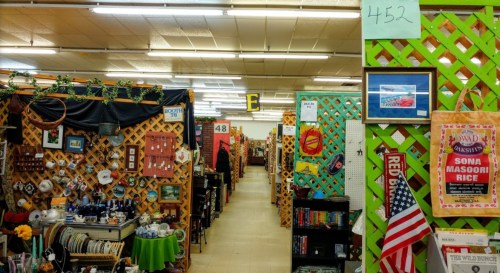 A vibrant indoor market with colorful displays, shelves of items, and decorative walls, creating a lively shopping atmosphere.
