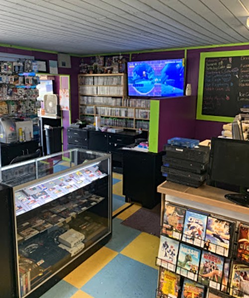 A colorful video rental store interior with shelves of DVDs, a display case, and a TV showing content.