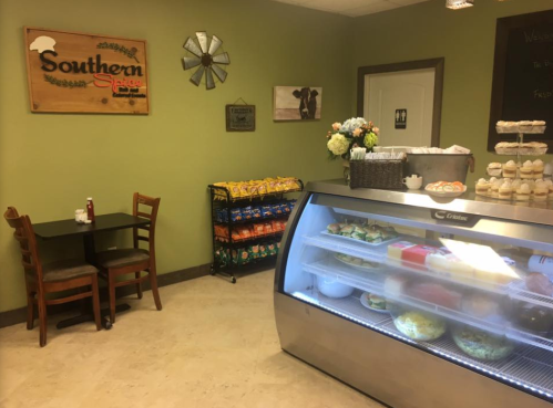 Cozy café interior with a sign reading "Southern Spice," a display case of food, and a small table for dining.