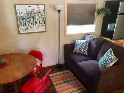 Cozy living space with a brown couch, red chairs, a wooden table, and a bicycle painting on the wall.