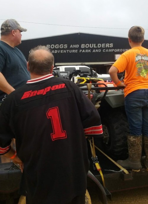 Three people loading an ATV onto a trailer at Boggs and Boulders Adventure Park and Campground.