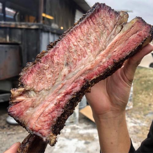 A close-up of a perfectly smoked beef brisket, showcasing its juicy, pink interior and charred exterior.