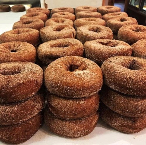A stack of freshly made, cinnamon-sugar coated donuts arranged neatly on a table.