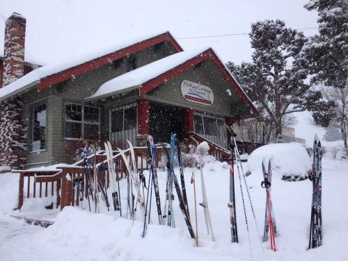 A cozy cabin covered in snow, with a row of skis lined up in front on a snowy day.