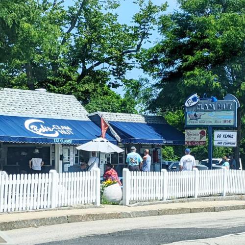 A seafood restaurant with blue awnings, people outside, and a sign celebrating 60 years in business.