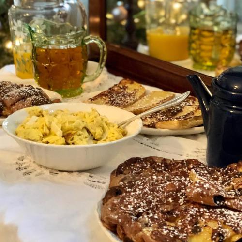 A cozy breakfast spread featuring scrambled eggs, sweet pastries, and drinks on a lace tablecloth.