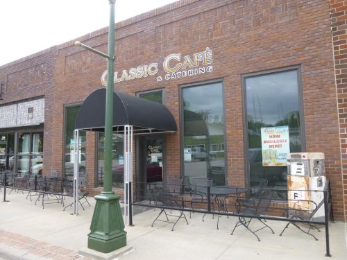 Exterior of Classic Café & Catering, featuring a black awning and outdoor seating along a brick building.