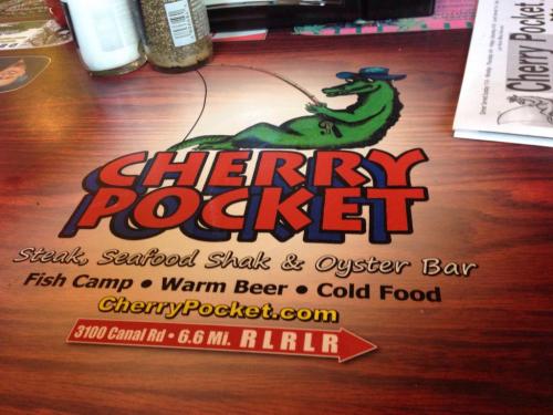 A wooden table with a colorful logo for "Cherry Pocket," featuring steak, seafood, and oyster bar offerings.