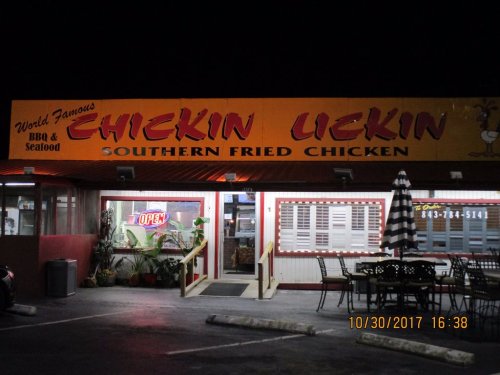 A brightly lit restaurant exterior at night, featuring a sign that reads "Chickin Lickin Southern Fried Chicken."