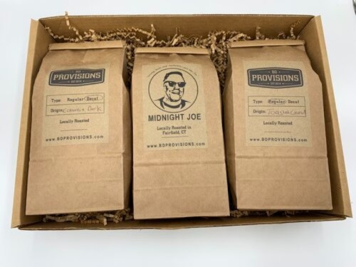 Three bags of coffee in a gift box, labeled "Regular Roast," "Midnight Joe," and "Regular Roast," with a rustic design.