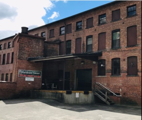 Exterior of a brick building with a loading dock, featuring a sign for "Hardcore Sweet" cupcake bakery.