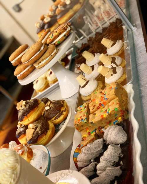 A display of assorted baked goods, including cookies, donuts, and brownies, arranged on elegant trays and stands.
