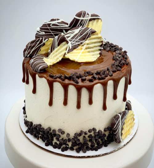 A round cake with chocolate ganache, topped with chocolate-covered cookies and chocolate chips.