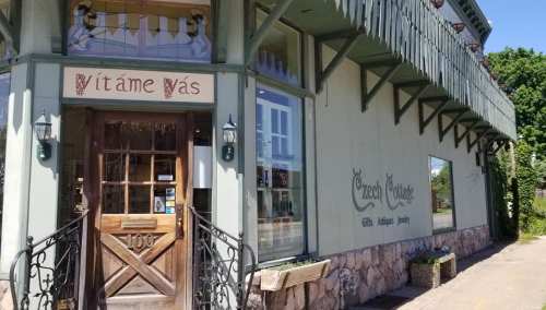 A charming storefront with a wooden door, green exterior, and decorative signage reading "Czech Cottage."