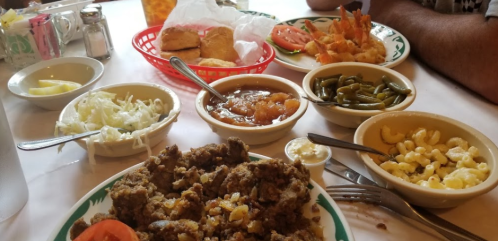 A table spread with various dishes, including fried shrimp, coleslaw, green beans, macaroni, and a main dish.