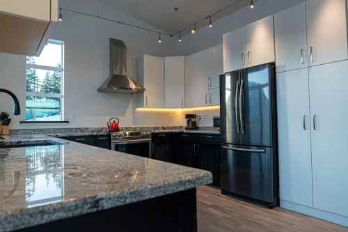 Modern kitchen with granite countertops, stainless steel appliances, and white cabinetry, featuring warm under-cabinet lighting.