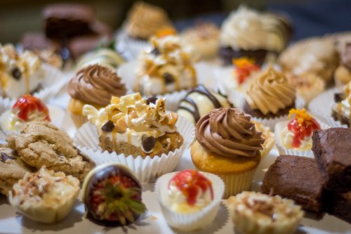 A colorful assortment of cupcakes, cookies, and desserts arranged on a table, showcasing various toppings and flavors.