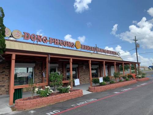Exterior of Dong Phuong Restaurant and Bakery, featuring a brick facade and a sign under a blue sky with clouds.