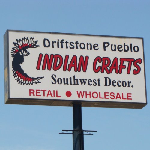 Sign for Driftstone Pueblo Indian Crafts, featuring "Indian Crafts" in bold red letters, promoting retail and wholesale.