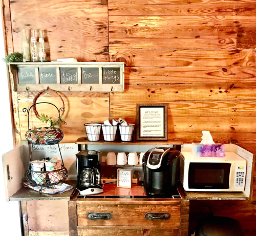 Cozy kitchen corner with a coffee maker, microwave, and decorative shelves against a wooden wall.