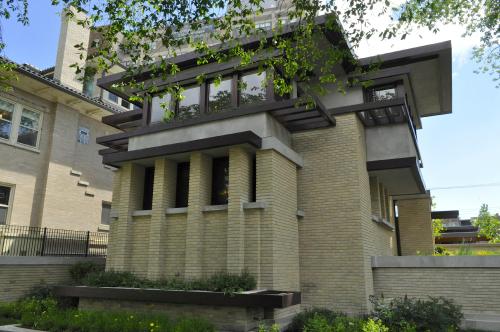 A modern architectural building with a mix of brick and concrete, featuring large windows and a unique roof design.