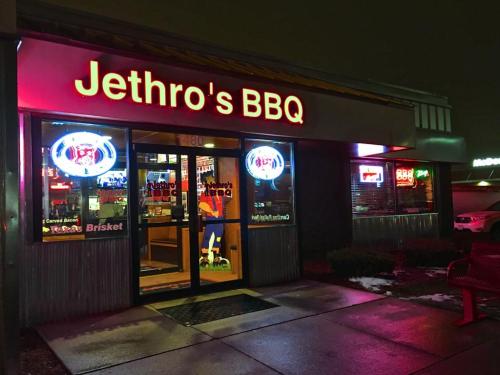 Exterior of Jethro's BBQ at night, featuring bright signage and neon lights, with a welcoming entrance.