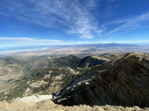 A panoramic view of mountains and valleys under a blue sky with scattered clouds.