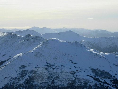 Snow-covered mountains stretch across the horizon under a soft, cloudy sky.