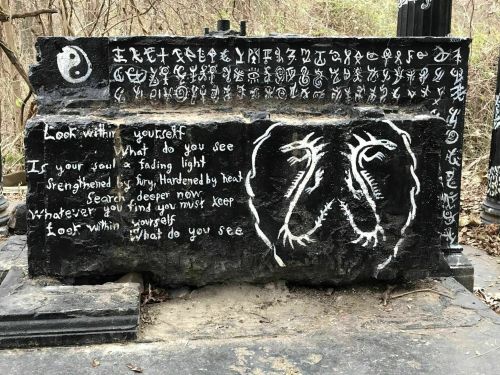 A stone slab covered in white symbols and text, featuring a yin-yang symbol and two dragon-like figures.