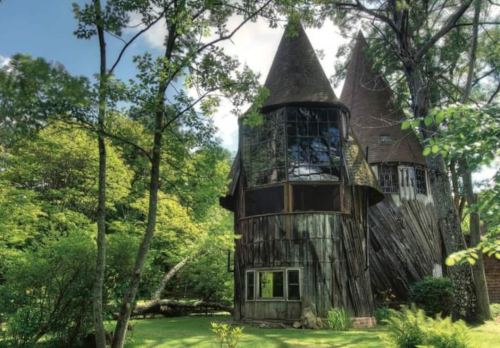 A whimsical, treehouse-like structure with pointed roofs, surrounded by lush greenery and trees.