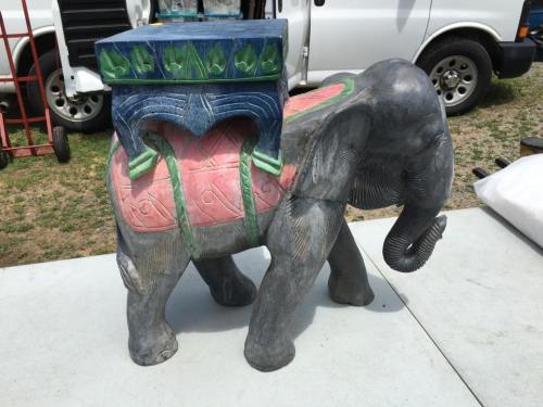A decorative elephant statue with a colorful, ornate box on its back, set on a grassy surface.