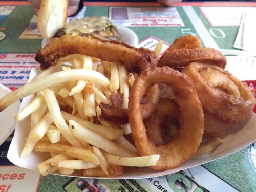 A plate of crispy onion rings and golden French fries served in a paper tray.