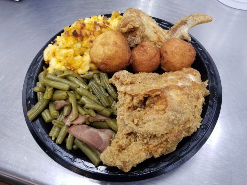 A plate of fried chicken, green beans, macaroni and cheese, cornbread muffins, and a side of ham.