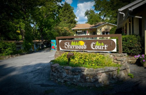 Sign for Sherwood Court, surrounded by greenery, with a pathway leading to buildings in a serene setting.