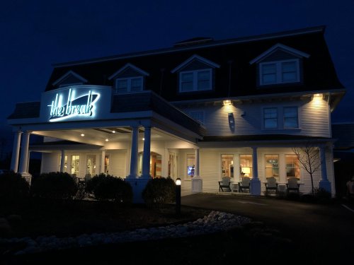 A well-lit building at night with a sign reading "the break," featuring a welcoming entrance and outdoor seating.