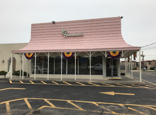 Exterior of Gambino's restaurant featuring a pink roof and decorative banners, with a parking lot in front.