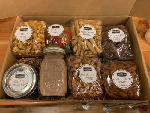 A box filled with various snacks: caramel corn, gummy bears, pretzels, chocolate peanut butter, and more.