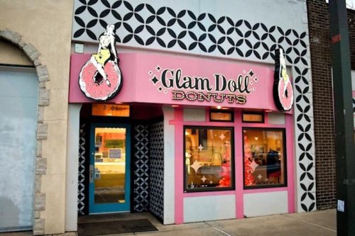 Exterior of Glam Doll Donuts shop featuring a pink sign with donuts and a stylish geometric pattern on the walls.