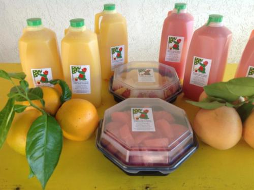 A colorful display of fruit juices in bottles, fresh fruits, and a container of mixed berries on a bright yellow table.